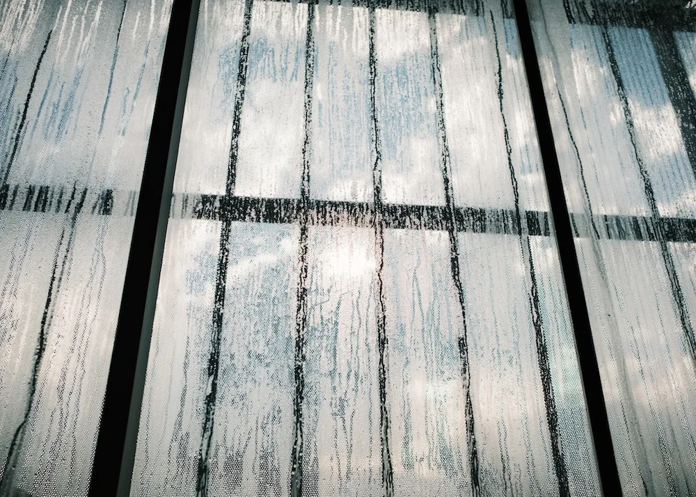 Panel textil con líneas verticales y reflejos, como trama visual de ondas sonoras.