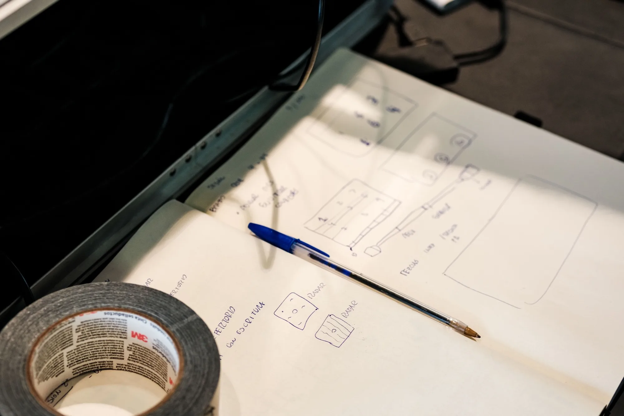 Mesa de trabajo con croquis técnicos, lápiz y cinta adhesiva para planificar el montaje sonoro.