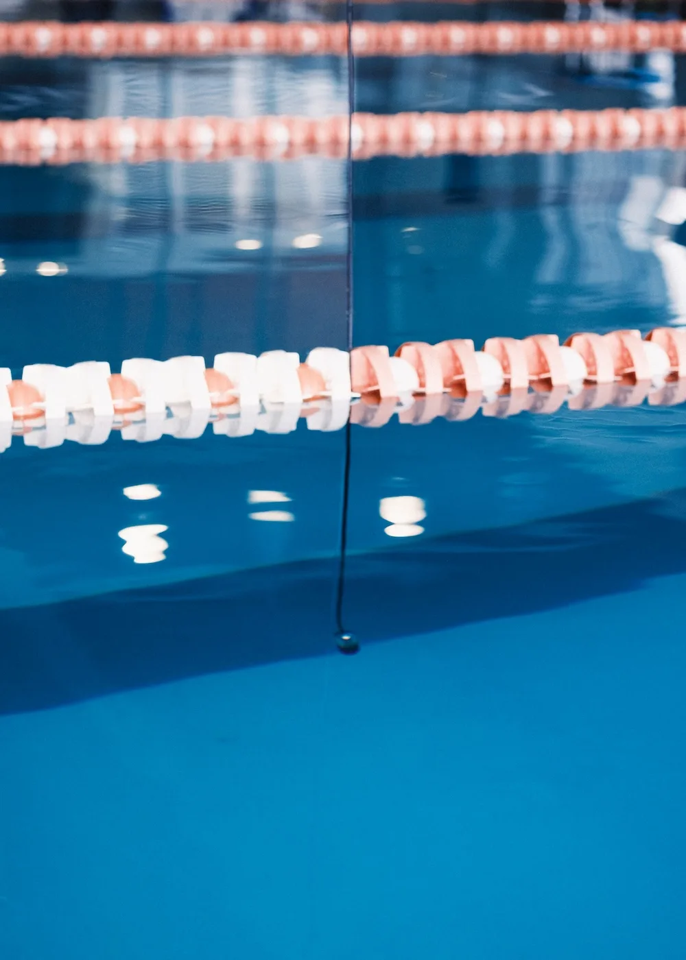 Cuerda de carril y reflejo del agua en la piscina, con una línea vertical suspendida en el centro.