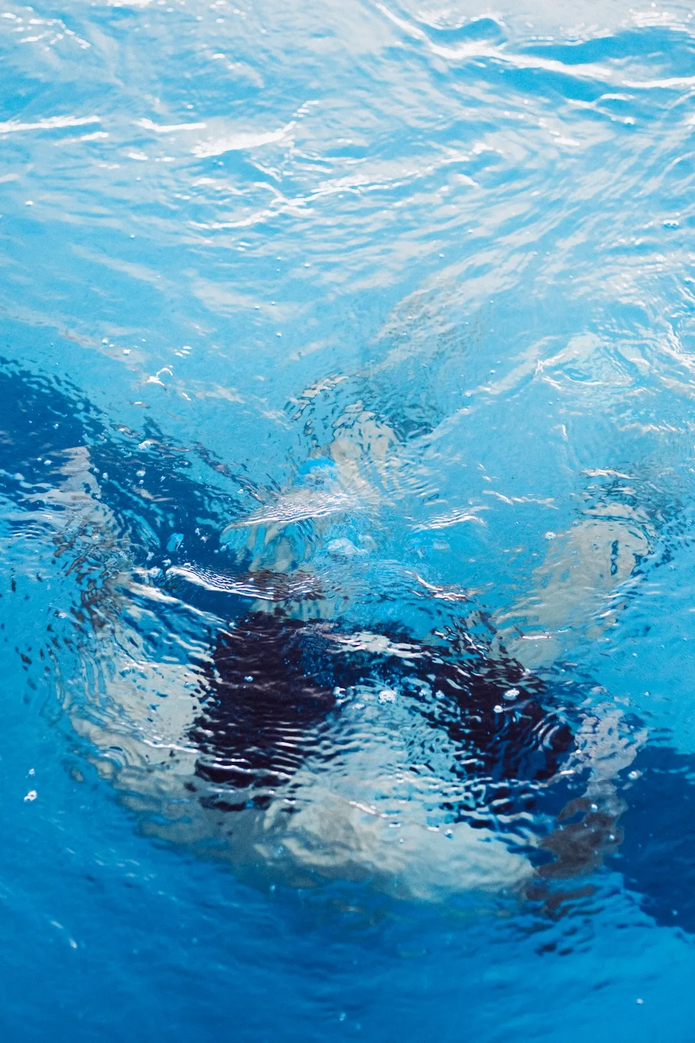 Figura de una persona semisumergida vista a través de la superficie ondulada del agua.